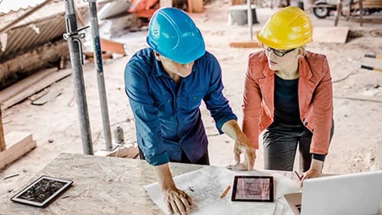 Two architects viewing digital tablet at construction site
