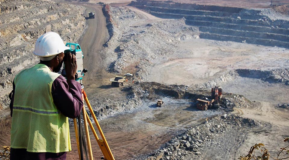 A locally employed surveyor at an open-pit copper mine in Zambia