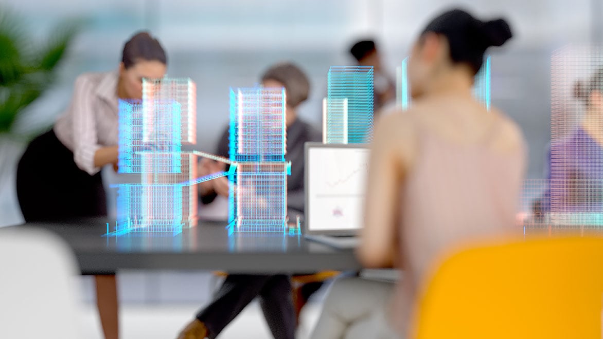 Businesswomen work in conference room with virtual cityscape projected in front of them 