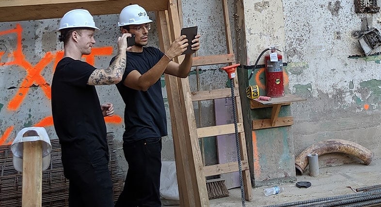 Two SHoP architects use an AR app to overlay a building model onto a jobsite in industrial outdoor setting 