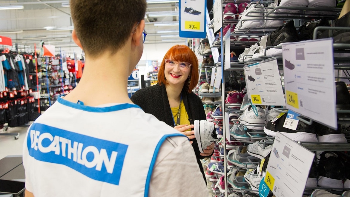 Employees review a shoe display at a Decathlon store.